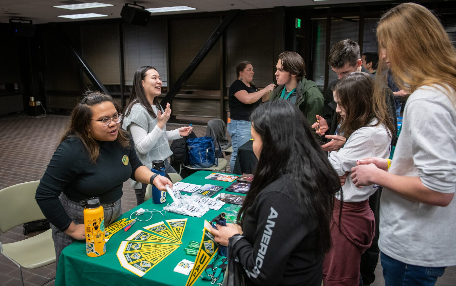 UAA admissions counselors Daphne Ang and Elise Wood talk with teams of students from around the state during the opening event in the student union as UAA hosts the Alaska Academic Decathlon 2023 State Competition.