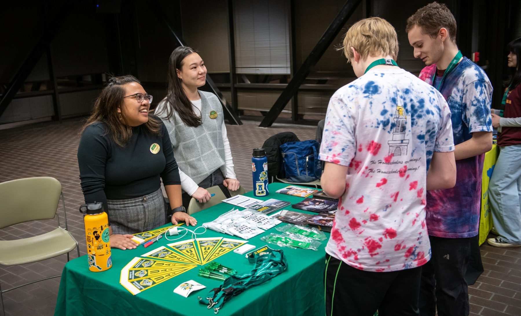UAA admissions counselors Daphne Ang and Elise Wood talk with teams of students from around the state during the opening event in the student union as UAA hosts the Alaska Academic Decathlon 2023 State Competition.